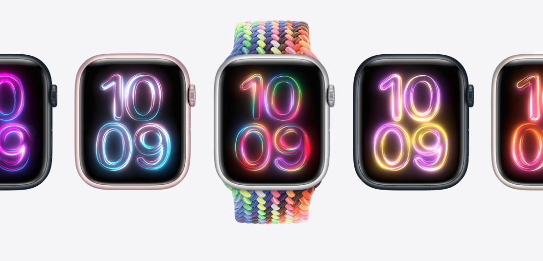 나란히 놓인 여러 개의 Apple Watch Series 9. 가운데 모델은 다채로운 색깔의 새로운 네온 빛 프라이드 에디션 브레이드 솔로 루프를 장착하고 있습니다. 각각의 시계 화면에는 서로 다른 색깔의 ‘프라이드 래디언스’ 시계 페이스가 보입니다.